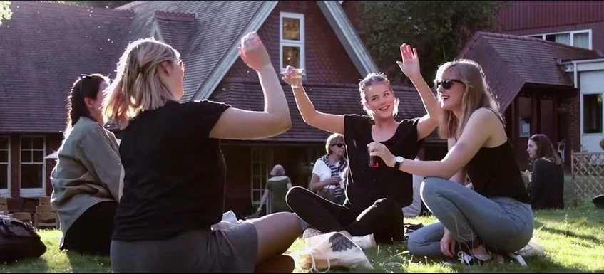 Adult students enjoying social time in Loxdale English Centre garden with Victorian building backdrop in Brighton